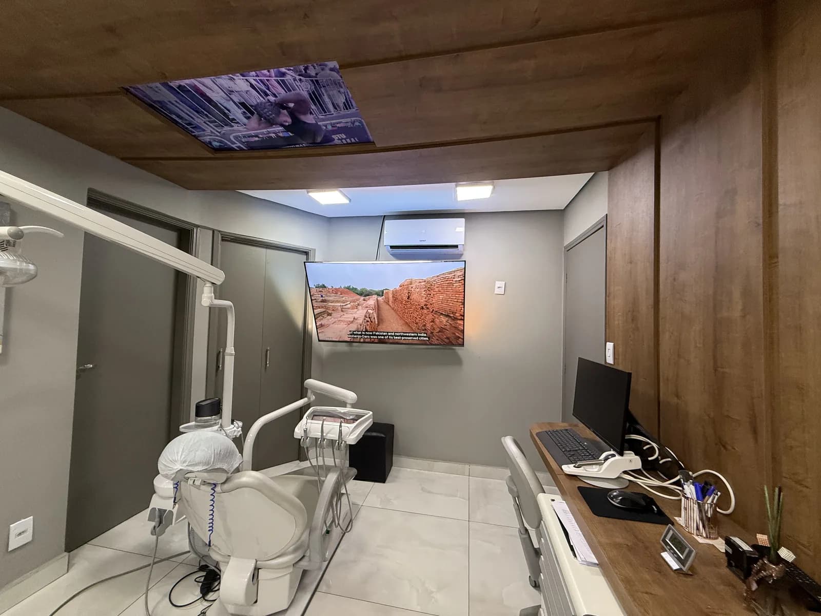 Consultório com teto de madeira e painel de luz com paisagem sobre a cadeira
